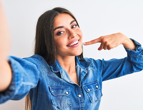 Smiling woman pointing to her white teeth
