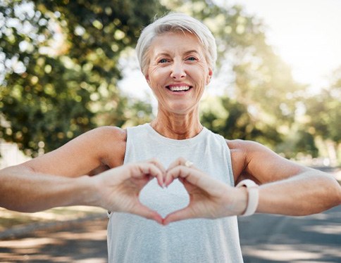 Smiling lady makes shape of heart with her hands