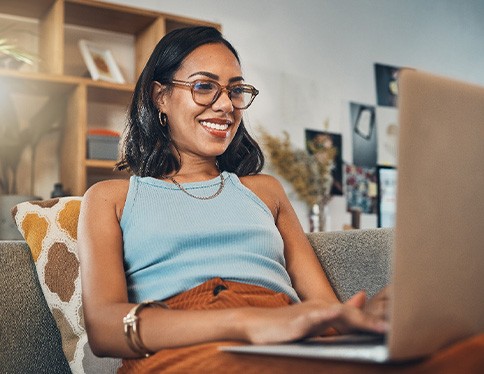 Woman smiling while working on laptop at home