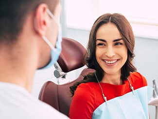 Woman smiling at dentist while sitting in treatment chair