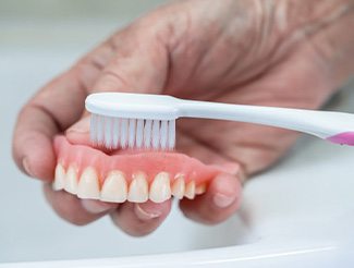 Denture being brushed