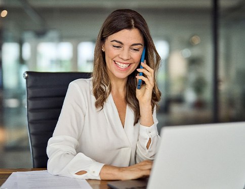 Woman smiling while talking on phone in office