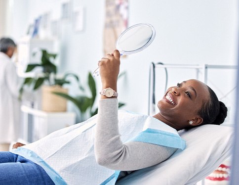 Woman smiling at reflection in handheld mirror