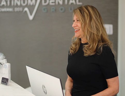 Friendly dental team member smiling behind the reception desk