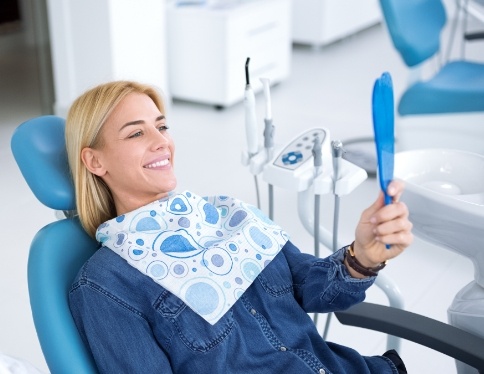 Woman looking at smile during dental checkup and teeth cleaning visit