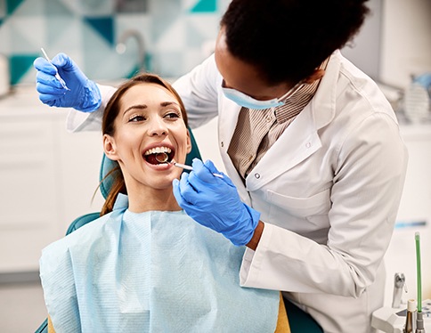 Woman smiling with dentist while reviewing X-ray