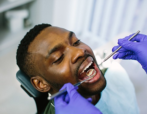 Woman in treatment chair smiling at dental hygienist