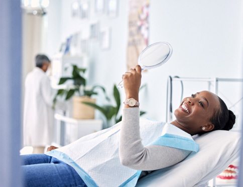 Woman smiling at reflection in handheld mirror