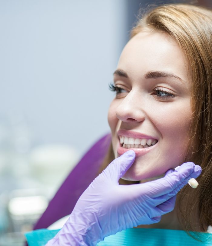 Dentist examining dental patient's smile after restoration with dental crowns