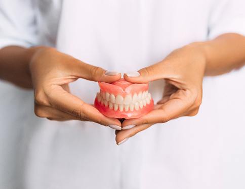 a person holding dentures in San Juan Capistrano