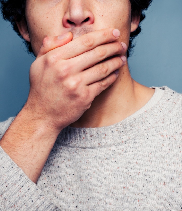 Man in need of emergency dentistry covering mouth