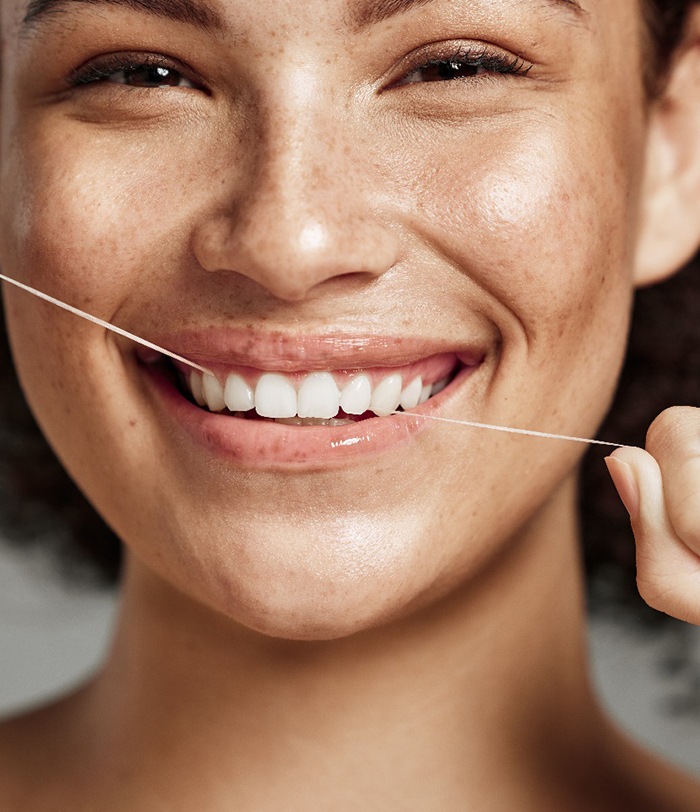 Facial closeup of woman with freckles flossing her upper arch