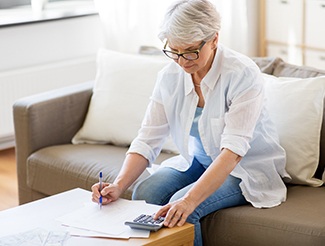 Woman calculating how to make dental implants in San Juan Capistrano affordable 