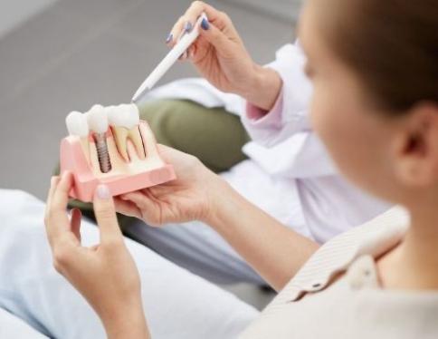 Dentist and patient looking at model smile with dental implant supported replacement tooth