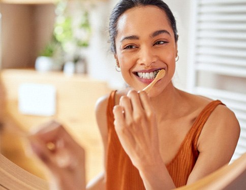 Woman smiling while brushing her teeth
