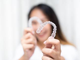 Patient holding up clear aligners and smiling