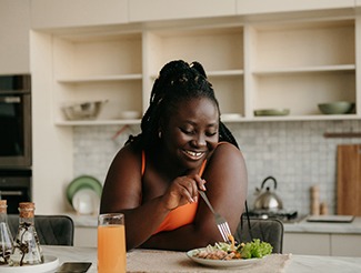 Smiling woman eating healthy lunch at home