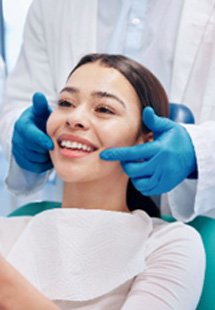 Mujer sonriendo a su reflejo mientras el dentista señala su exposición