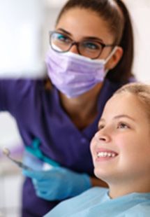 Dental assistant and child smiling while looking at X-ray