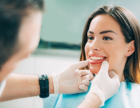 A woman admiring her treated smile with a hand mirror