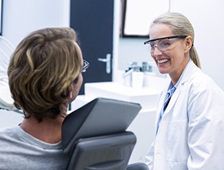 Dentist smiling at patient in treatment room