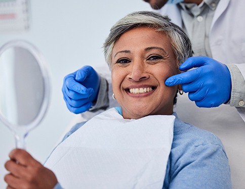 Woman smiling while holding handheld mirror