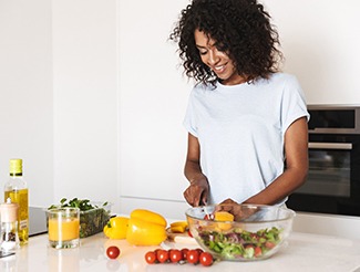 Woman smiling while preparing healthy meal at home