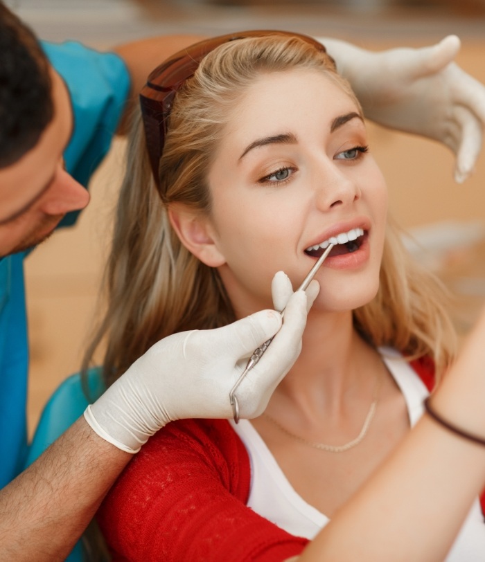 Woman looking at her smile after porcelain veneers treatment