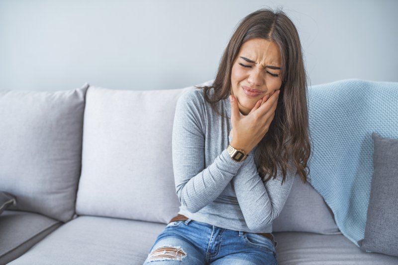 person with toothache holding their cheek