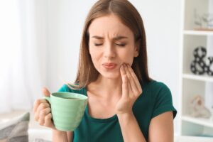 Woman experiencing tooth sensitivity after drinking coffee.